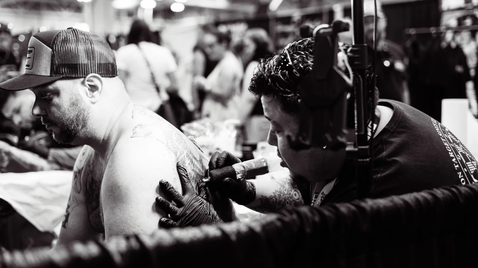 Tattoo artist working on a client's shoulder in a studio