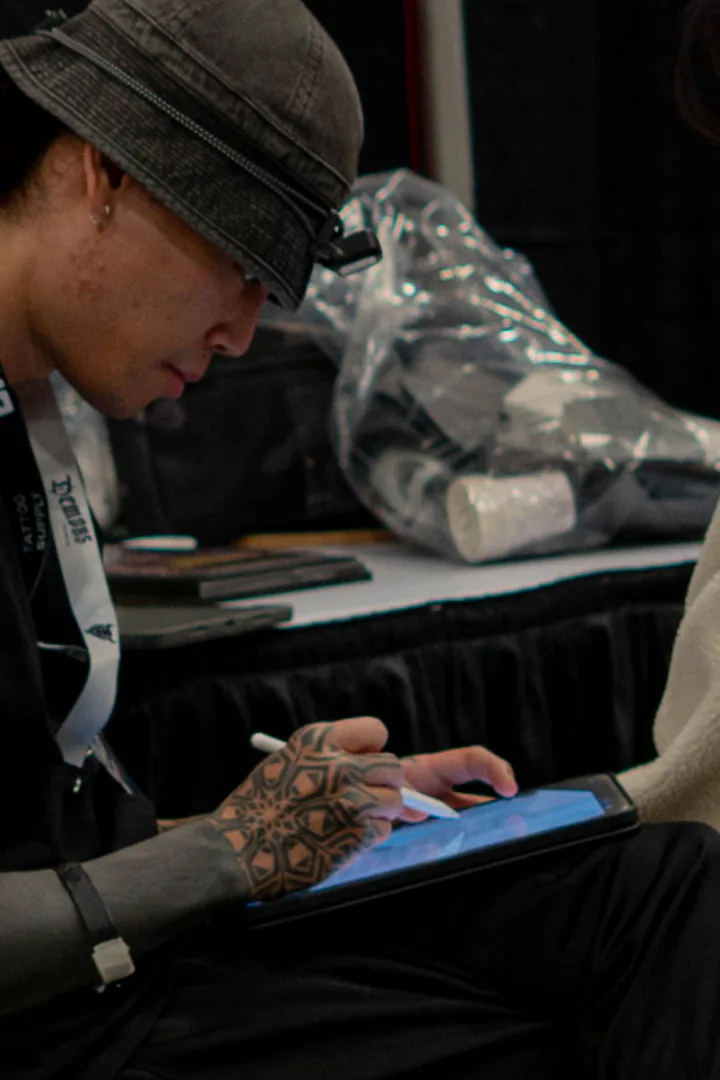 Tattoo artist working on a drawing with a tablet and stylus